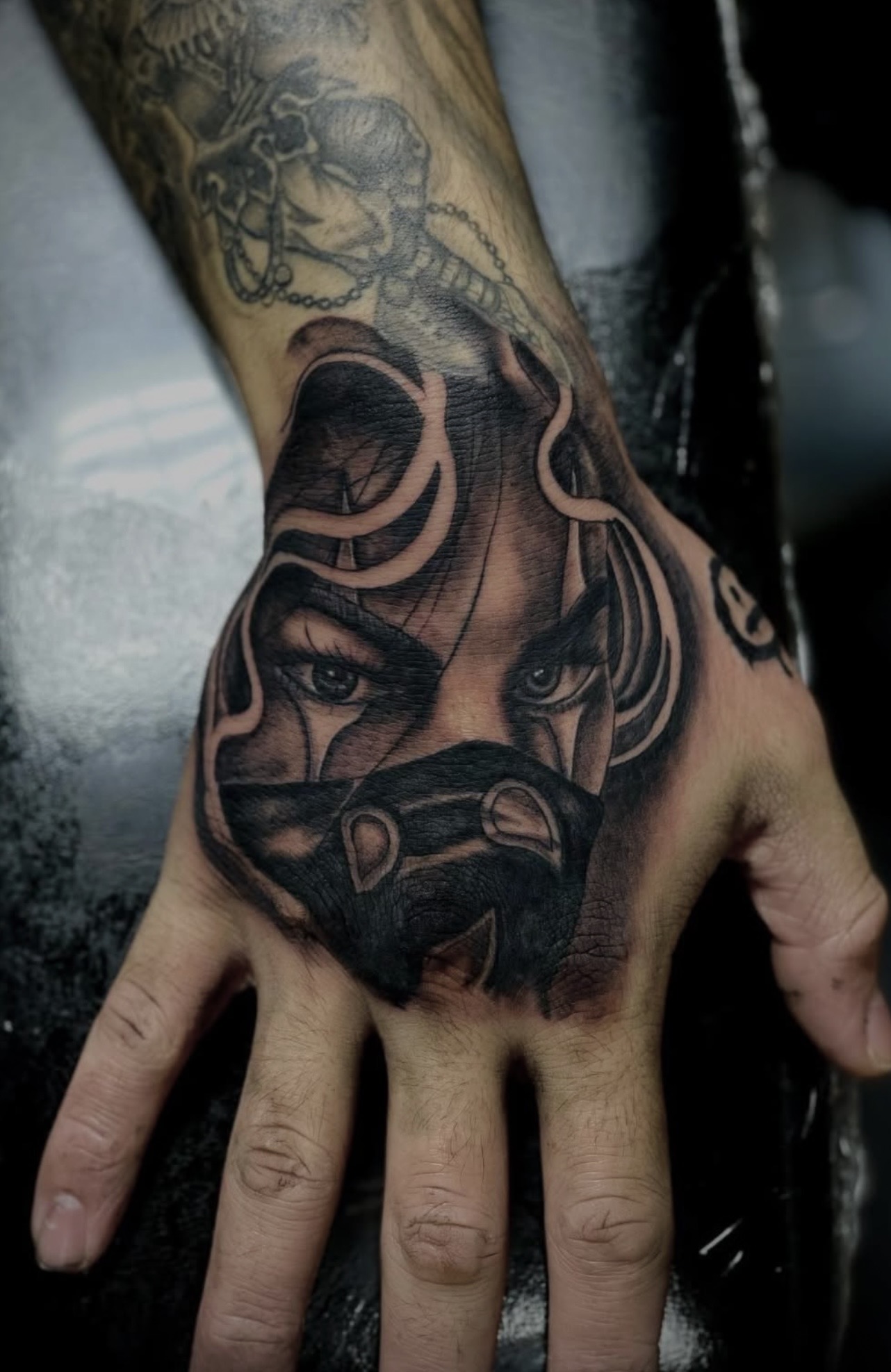 Black and grey masked figure hand tattoo